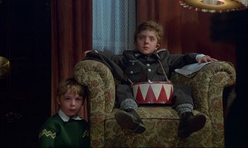 Movie still from “The Tin Drum” (1979), directed by Volker Schlöndorff – Two young boys sitting on a chair in a living room; Medium shot, Low angle