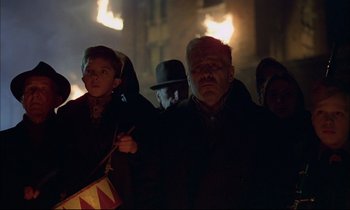 Movie still from “The Tin Drum” (1979), directed by Volker Schlöndorff – A group of people standing in the dark holding candles; Medium shot, Low angle