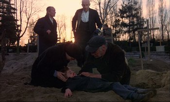 Movie still from “The Tin Drum” (1979), directed by Volker Schlöndorff – A group of men standing around a young boy; Wide shot, High angle