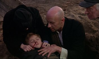 Movie still from “The Tin Drum” (1979), directed by Volker Schlöndorff – A man and a child are lying on the ground; Medium shot, High angle