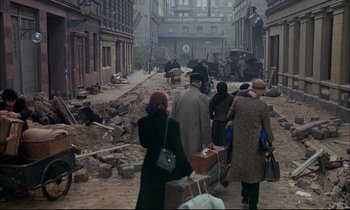 Movie still from “The Tin Drum” (1979), directed by Volker Schlöndorff – A group of people walking down a street; Wide shot, High angle