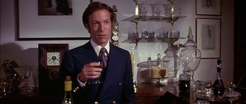 Movie still from “The Towering Inferno” (1974), directed by John Guillermin – A man in a suit and tie holding a glass of wine; Medium shot, Low angle