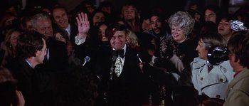 Movie still from “The Towering Inferno” (1974), directed by John Guillermin – A man in a suit and tie waves to the crowd; Medium shot, High angle