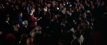 Movie still from “The Towering Inferno” (1974), directed by John Guillermin – A group of people standing in front of a crowd of onlookers; Wide shot, Over the shoulder angle