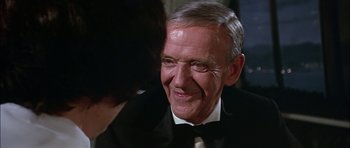 Movie still from “The Towering Inferno” (1974), directed by John Guillermin – An older man in a tuxedo smiling at a young woman; Close Up shot, Over the shoulder angle