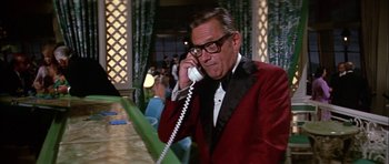 Movie still from “The Towering Inferno” (1974), directed by John Guillermin – An older man in a red jacket talking on a phone; Medium shot, Low angle