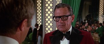 Movie still from “The Towering Inferno” (1974), directed by John Guillermin – An older man wearing a tuxedo and a bow tie; Close Up shot, Over the shoulder angle