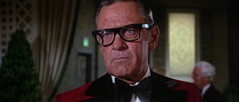 Movie still from “The Towering Inferno” (1974), directed by John Guillermin – An older man in a tuxedo wearing glasses; Close Up shot, Low angle