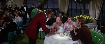 Movie still from “The Towering Inferno” (1974), directed by John Guillermin – A group of people sitting around a table at an event; Medium shot, Over the shoulder angle