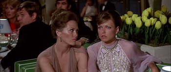 Movie still from “The Towering Inferno” (1974), directed by John Guillermin – Two women sitting next to each other at a party; Close Up shot, Over the shoulder angle