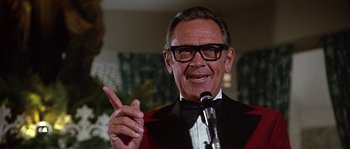 Movie still from “The Towering Inferno” (1974), directed by John Guillermin – An older man wearing a red jacket and a black bow tie; Close Up shot, Low angle
