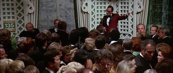 Movie still from “The Towering Inferno” (1974), directed by John Guillermin – A crowd of people gathered together in a room; Wide shot, Over the shoulder angle