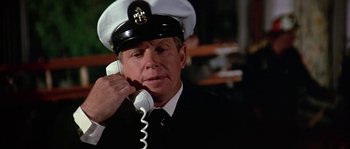 Movie still from “The Towering Inferno” (1974), directed by John Guillermin – A man wearing a hat is talking on a phone; Close Up shot, Low angle
