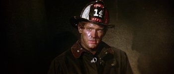 Movie still from “The Towering Inferno” (1974), directed by John Guillermin – A man in a fireman's uniform and helmet; Close Up shot, Low angle