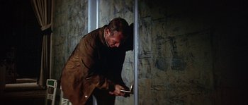 Movie still from “The Towering Inferno” (1974), directed by John Guillermin – A man in a brown jacket is holding a knife; Medium shot, Low angle