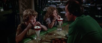 Movie still from “The Towering Inferno” (1974), directed by John Guillermin – Three people sitting at a table eating ice cream; Medium shot, High angle