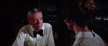 Movie still from “The Towering Inferno” (1974), directed by John Guillermin – An older man wearing a white shirt and a bow tie talking to a young man; Close Up shot, Over the shoulder angle