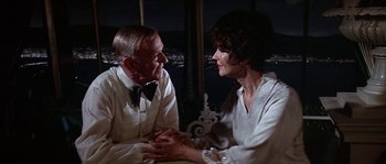 Movie still from “The Towering Inferno” (1974), directed by John Guillermin – An older man and a younger woman sitting at a table; Medium shot, High angle