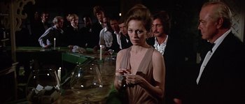 Movie still from “The Towering Inferno” (1974), directed by John Guillermin – A group of people standing around a bar; Medium shot, Over the shoulder angle