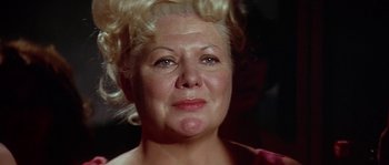 Movie still from “The Towering Inferno” (1974), directed by John Guillermin – An older woman with blonde curly hair looking at the camera; Close Up shot, Low angle