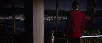 Movie still from “The Towering Inferno” (1974), directed by John Guillermin – A man standing in front of a window at night with a city in the background; Wide shot, Over the shoulder angle