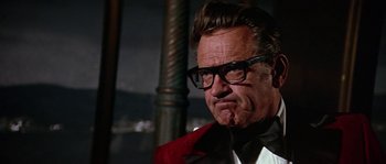 Movie still from “The Towering Inferno” (1974), directed by John Guillermin – An older man wearing glasses and a red jacket; Close Up shot, Low angle