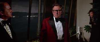 Movie still from “The Towering Inferno” (1974), directed by John Guillermin – An older man in a red jacket and a black bow tie; Medium shot, Low angle