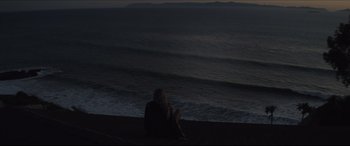 Movie still from “The Tribes of Palos Verdes” (2017), directed by Brendan Malloy – A woman sitting on the beach looking out at the ocean; Extreme Wide shot, High angle