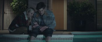 Movie still from “The Tribes of Palos Verdes” (2017), directed by Brendan Malloy – A man and a woman sitting next to each other on the ground; Medium shot, Low angle