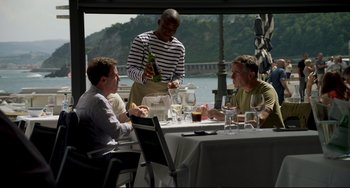 Movie still from “The Trip to Spain” (2017), directed by Michael Winterbottom – Three men are sitting at a table with wine glasses; Medium shot, Over the shoulder angle