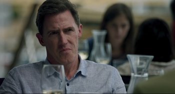 Movie still from “The Trip to Spain” (2017), directed by Michael Winterbottom – A person sitting at a table with wine glasses; Close Up shot, Over the shoulder angle
