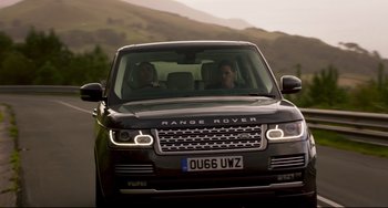 Movie still from “The Trip to Spain” (2017), directed by Michael Winterbottom – Two people sitting in the drivers seat of a range rover; Medium shot, Over the shoulder angle