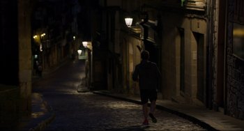 Movie still from “The Trip to Spain” (2017), directed by Michael Winterbottom – A man running down a street at night; Wide shot, High angle