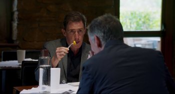 Movie still from “The Trip to Spain” (2017), directed by Michael Winterbottom – Two men are sitting at a table and one of them is eating a piece of food; Medium shot, Over the shoulder angle