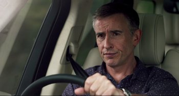 Movie still from “The Trip to Spain” (2017), directed by Michael Winterbottom – A person in a car holding a steering wheel; Close Up shot, Low angle
