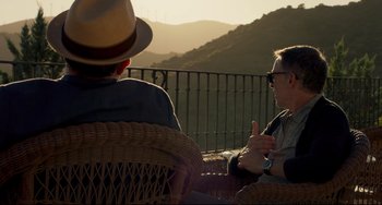 Movie still from “The Trip to Spain” (2017), directed by Michael Winterbottom – Two men are sitting outside talking to each other; Medium shot, Over the shoulder angle