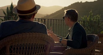Movie still from “The Trip to Spain” (2017), directed by Michael Winterbottom – Two men are sitting on a balcony talking; Medium shot, Over the shoulder angle