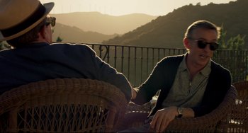 Movie still from “The Trip to Spain” (2017), directed by Michael Winterbottom – Two people sitting on a chair in the sun; Medium shot, Over the shoulder angle
