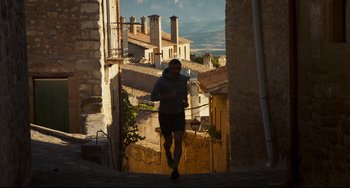 Movie still from “The Trip to Spain” (2017), directed by Michael Winterbottom – A man is walking down the street in the evening; Wide shot, Low angle