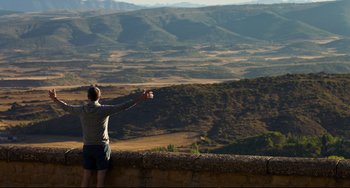 Movie still from “The Trip to Spain” (2017), directed by Michael Winterbottom – A man standing on a ledge looking out over a valley; Extreme Wide shot, Low angle