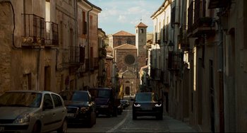 Movie still from “The Trip to Spain” (2017), directed by Michael Winterbottom – Cars are parked on the side of the street; Extreme Wide shot, Low angle