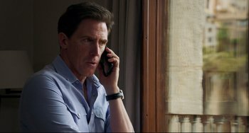 Movie still from “The Trip to Spain” (2017), directed by Michael Winterbottom – A man is talking on a cell phone by a window; Close Up shot, Over the shoulder angle