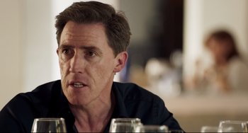 Movie still from “The Trip to Spain” (2017), directed by Michael Winterbottom – A person sitting at a table; Close Up shot, Over the shoulder angle