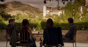 Movie still from “The Trip to Spain” (2017), directed by Michael Winterbottom – Two women sitting on a bench looking out at a castle; Extreme Wide shot, High angle