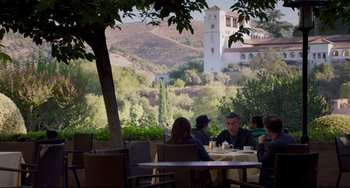 Movie still from “The Trip to Spain” (2017), directed by Michael Winterbottom – A group of people sitting at a table outside; Wide shot, Over the shoulder angle
