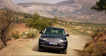 Movie still from “The Trip to Spain” (2017), directed by Michael Winterbottom – A range rover driving down a dirt road; Extreme Wide shot, High angle