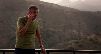 Movie still from “The Trip to Spain” (2017), directed by Michael Winterbottom – A man is talking on a cell phone while standing outside; Medium shot, Low angle