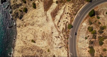 Movie still from “The Trip to Spain” (2017), directed by Michael Winterbottom – An aerial view of a road in the middle of a desert; Extreme Wide shot, Overhead angle