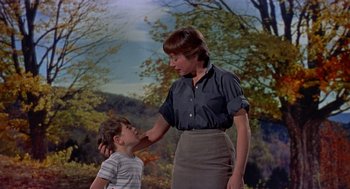 Movie still from “The Trouble with Harry” (1955), directed by Alfred Hitchcock – A woman and a boy standing next to each other in front of trees; Medium shot, Low angle