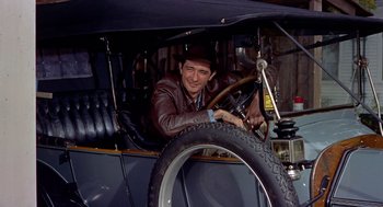 Movie still from “The Trouble with Harry” (1955), directed by Alfred Hitchcock – A man sitting in the driver's seat of an antique car; Medium shot, Low angle